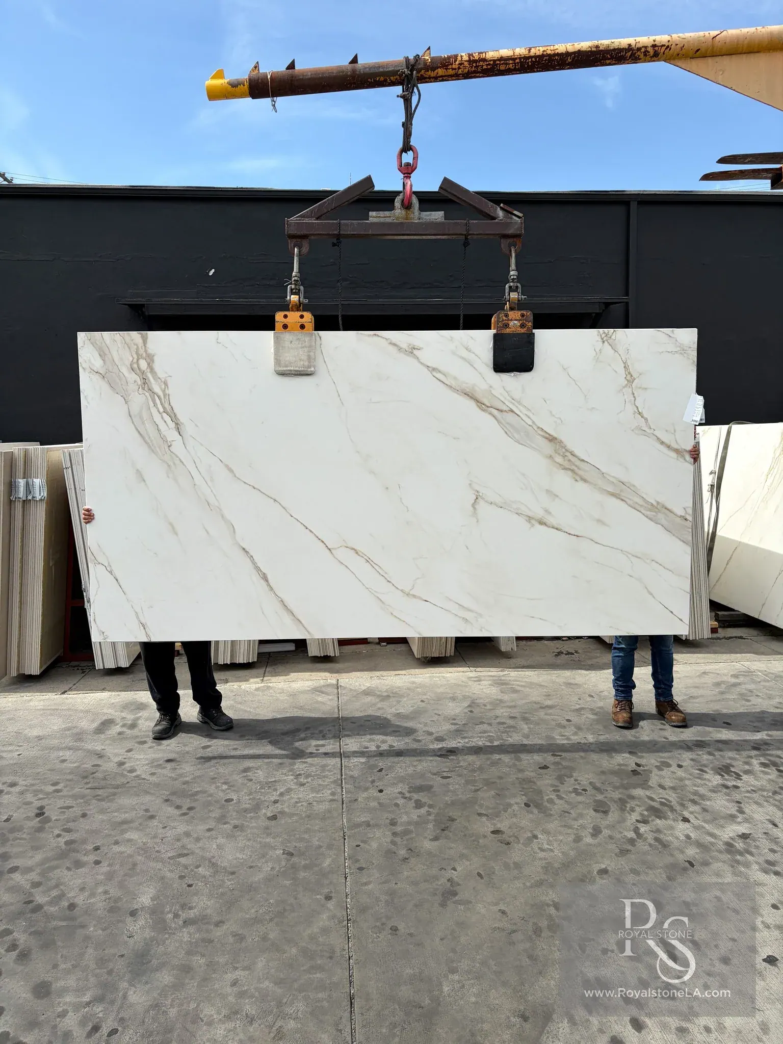 Second view of the same ABK Calacatta Gold porcelain panel on the crane, showing the diagonal gold vein network running corner to corner across the honed white ground