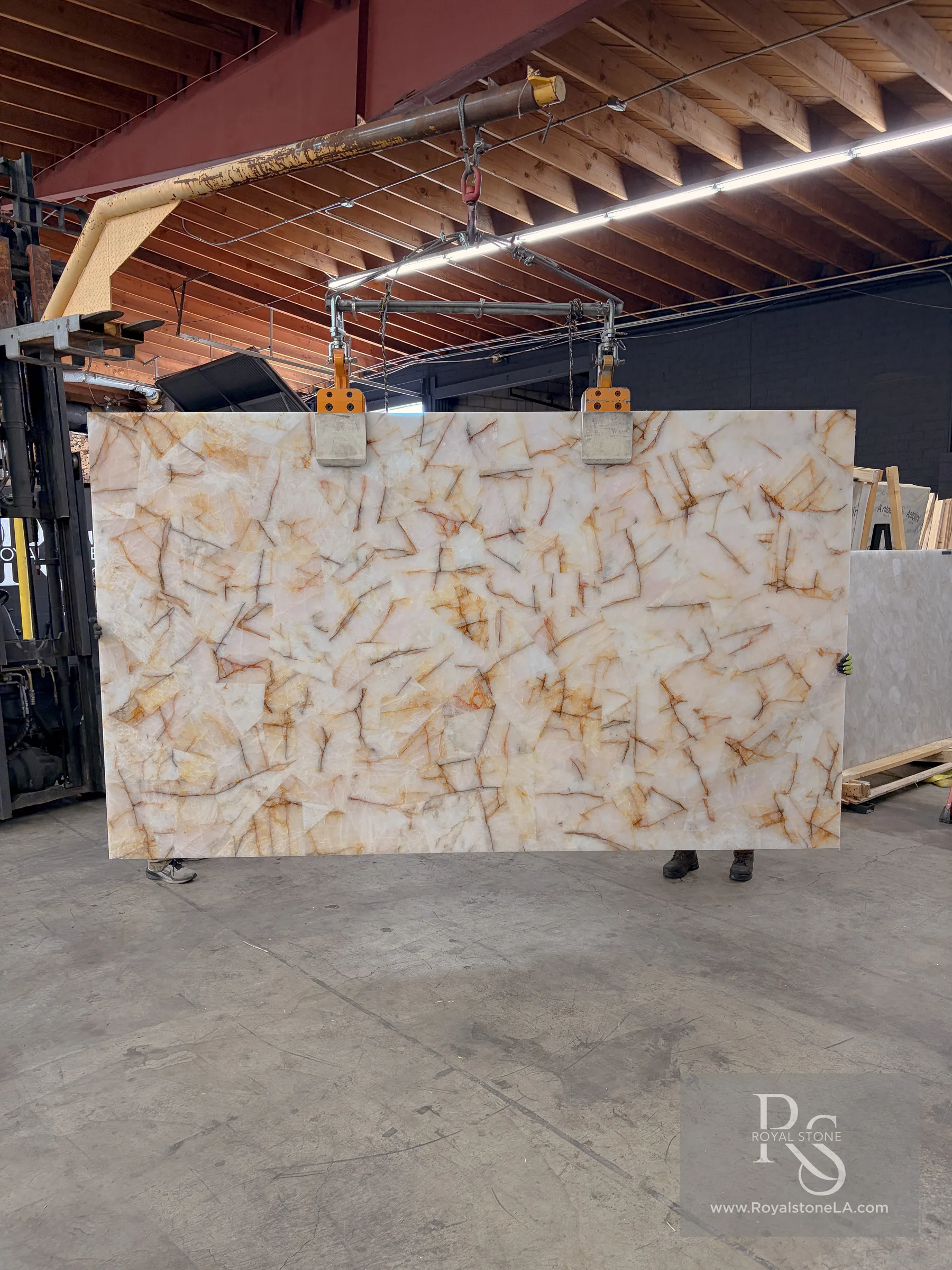 2cm Antolini Hematoid Quartz Light semiprecious stone slab, Hamsa Blue polished, lot X250129, 76 by 128 inches, white quartz with golden hematite veining, hanging from a crane at the Royal Stone Los Angeles warehouse