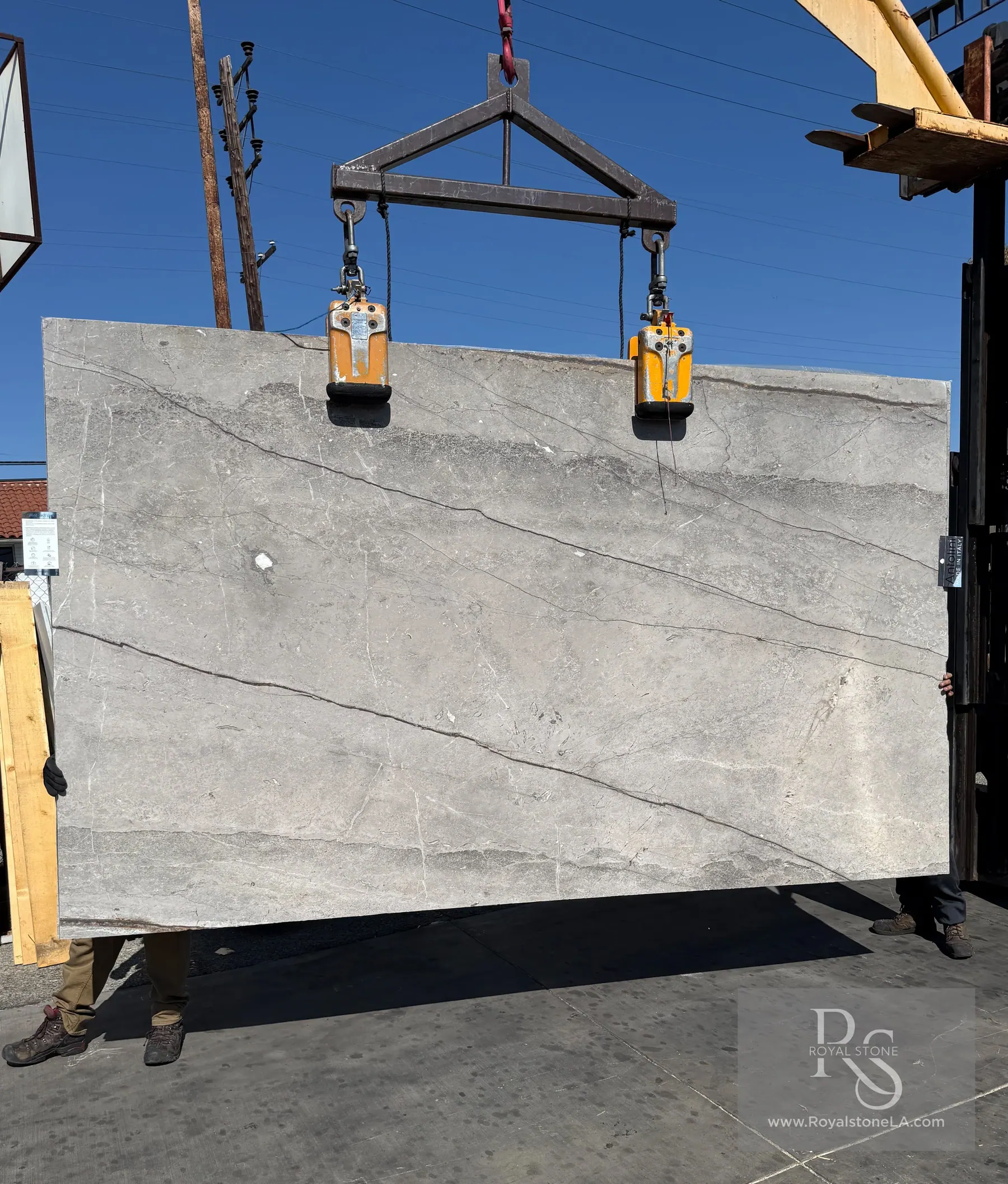 Antolini Jurassic Taupe Silver Roots honed marble slab lifted by crane at the Royal Stone yard, showing soft pewter-gray field with diagonal root-like veining
