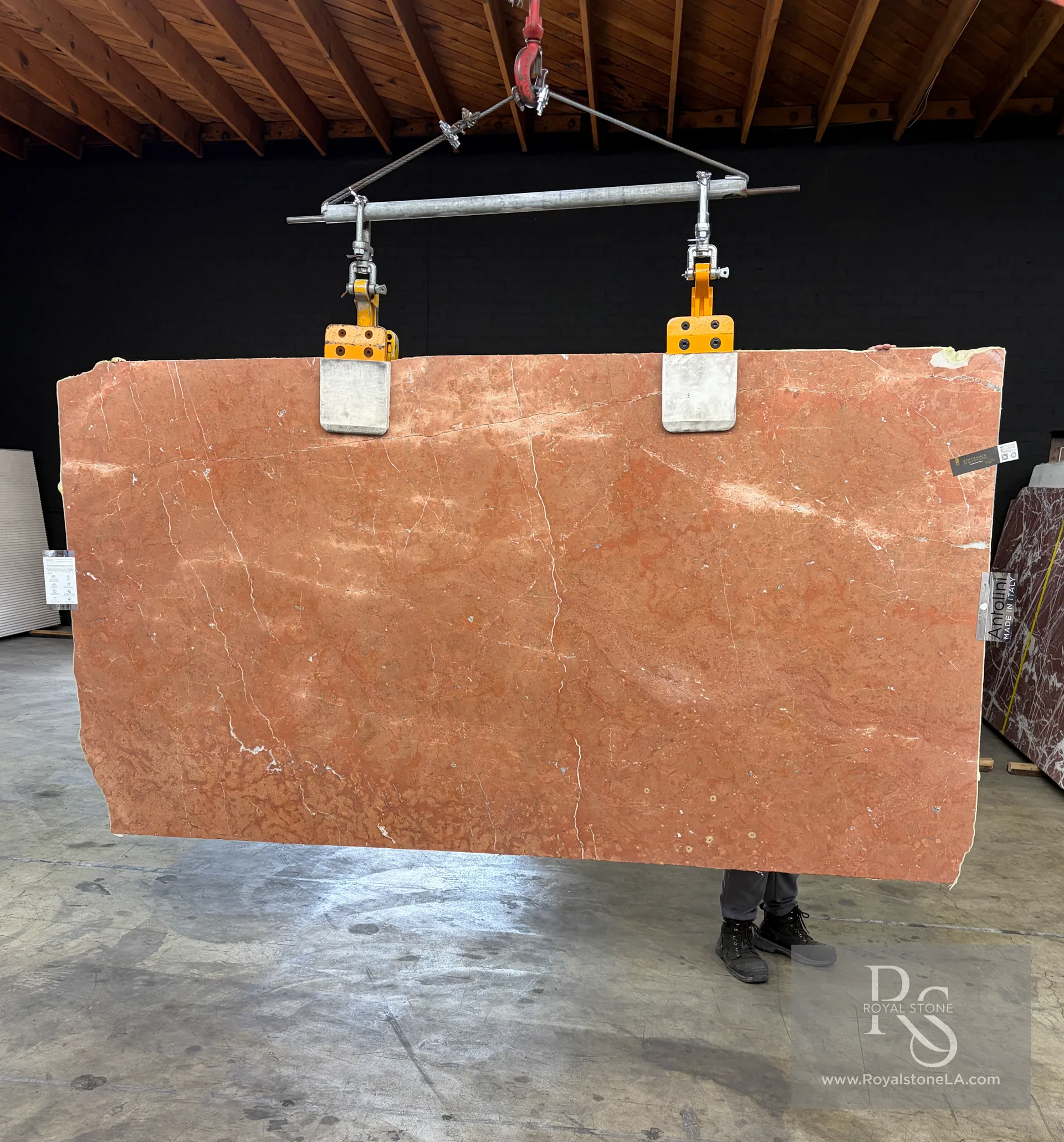 2cm Antolini Rojo Alicante honed marble slab, 61 by 113 inches, warm brick-red and terracotta field with quiet white calcite veining, lifted on the overhead crane at the Royal Stone yard in Los Angeles