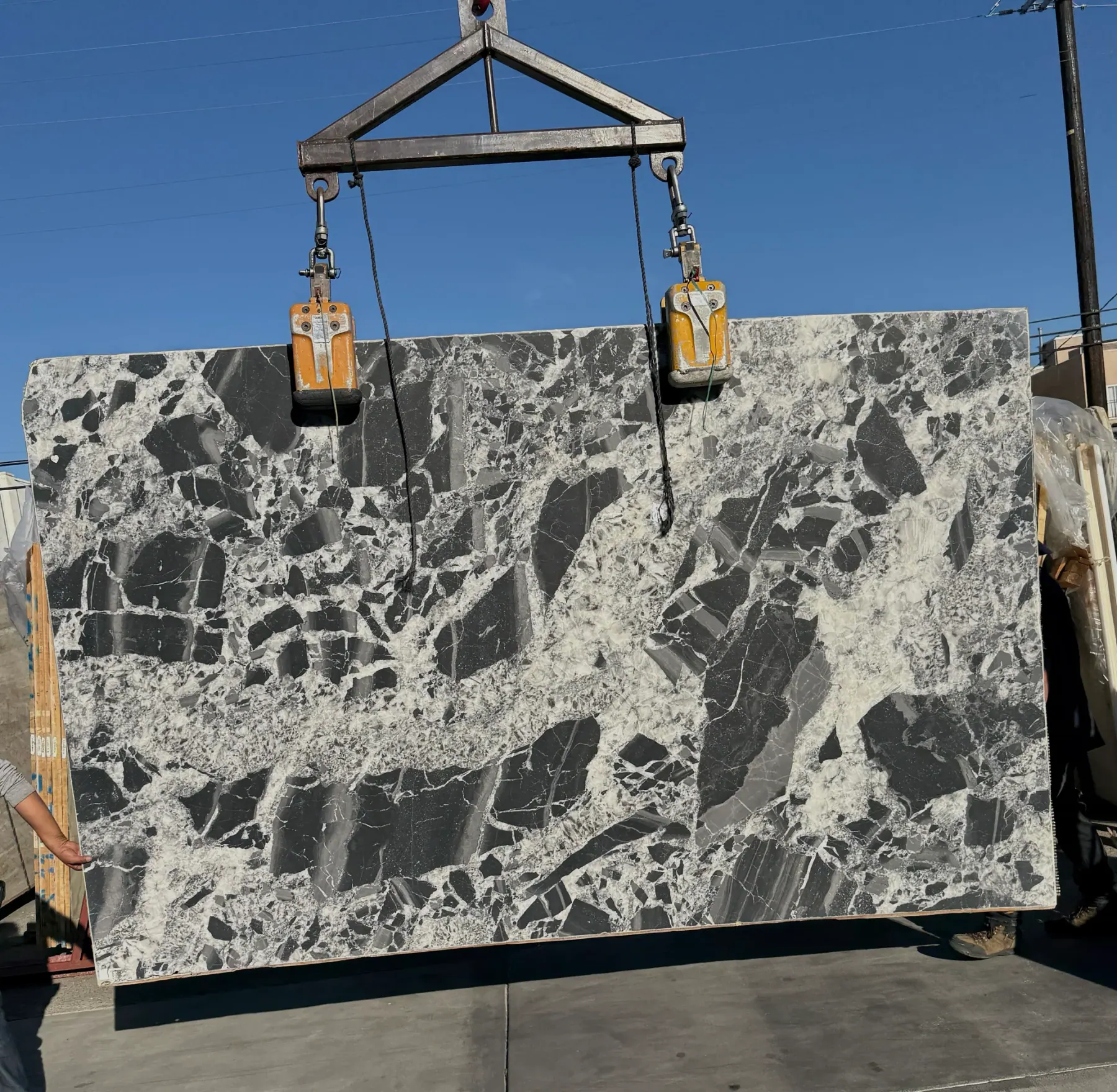 Antolini Cristallo Nero quartzite slab on the crane, fractured black blocks in white crystalline quartz matrix, honed matte finish, 80 by 128 inches