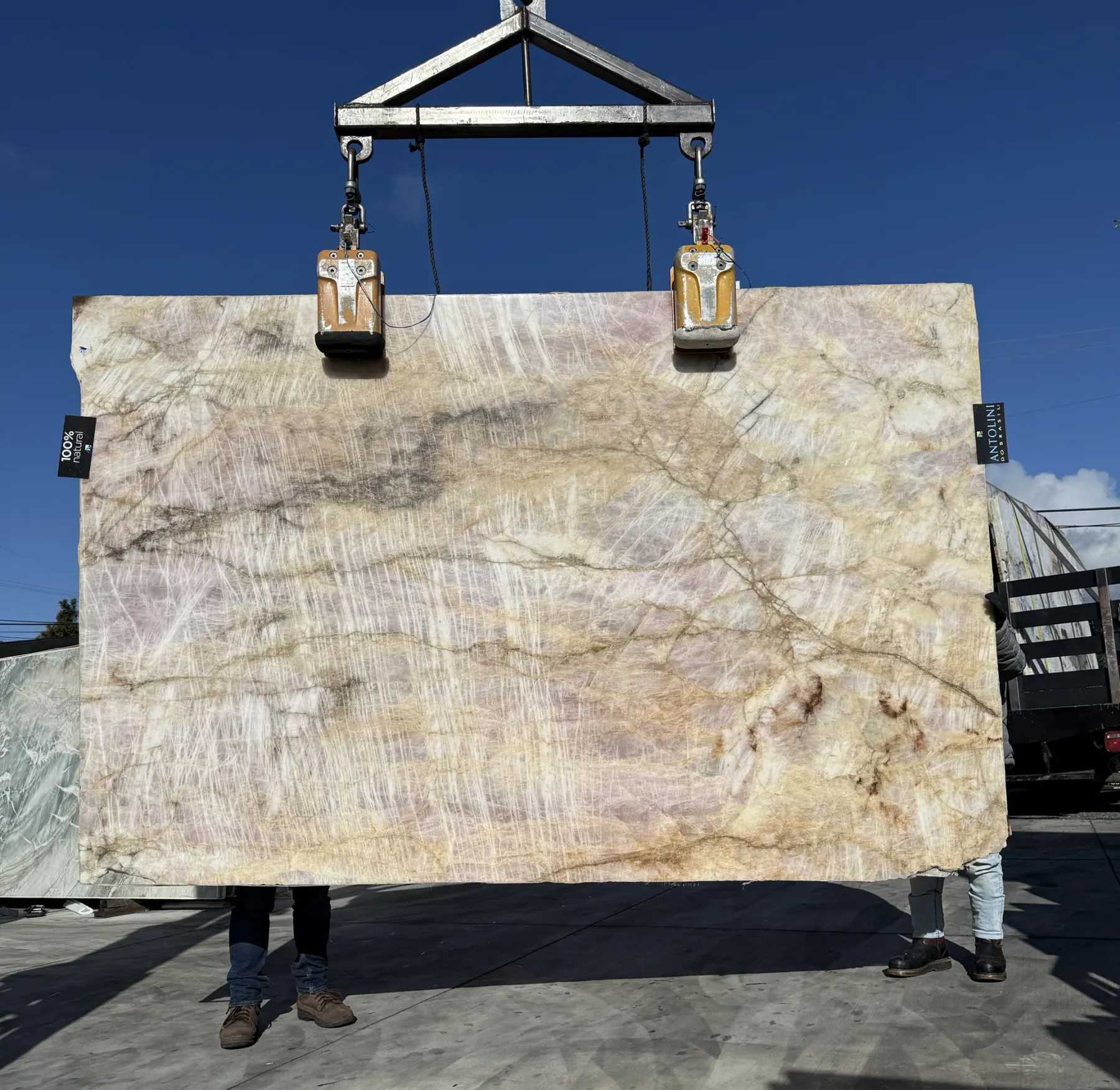 Antolini Cristallo Tropicale quartzite slab on the crane, warm rose pink and honey field with fine quartz needling and rust veining, polished finish, 71 by 109 inches