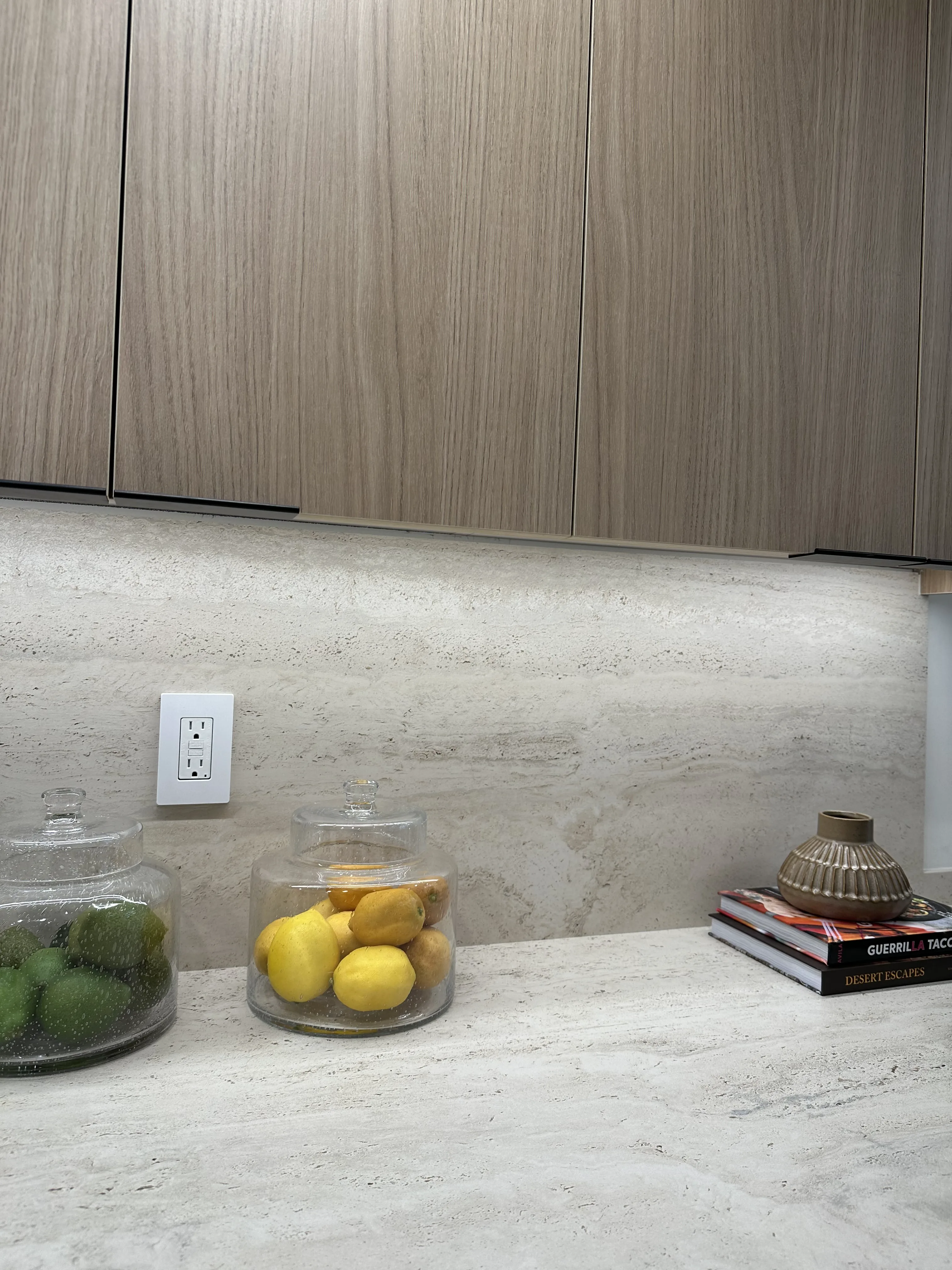 ABK Navona Bone vein-cut 3D honed porcelain installed as a Newport Beach kitchen countertop, with the slab's long horizontal banding running continuously across the island and mitred down to the apron