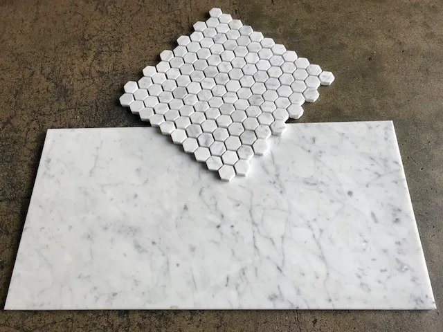 Honed Italian Carrara White marble 1-inch mini hexagon mosaic sample above a honed field tile, on concrete