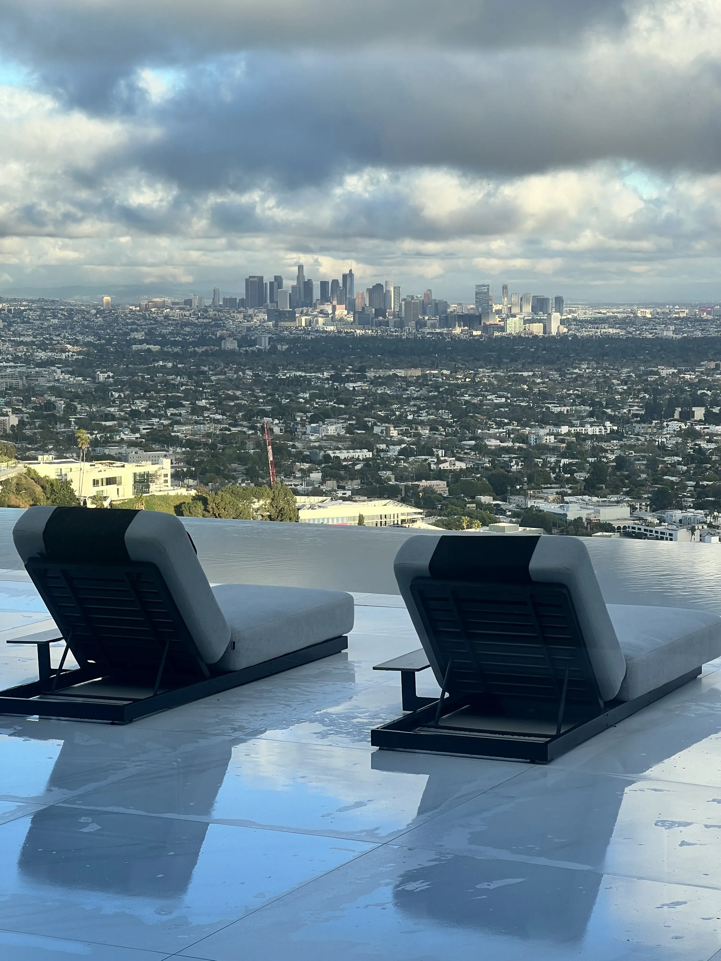 48 by 48 Eco Calacatta Soft Vein Honed porcelain large-format tile installed as an exterior wet-area patio surface, with chaise lounges on the porcelain deck overlooking the Los Angeles skyline