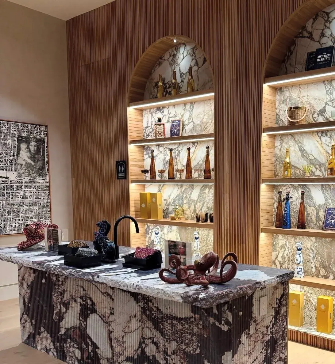 Bar millwork backed by Calacatta Viola marble in arched fluted-oak niches, with a Calacatta Viola bar counter and fluted base.