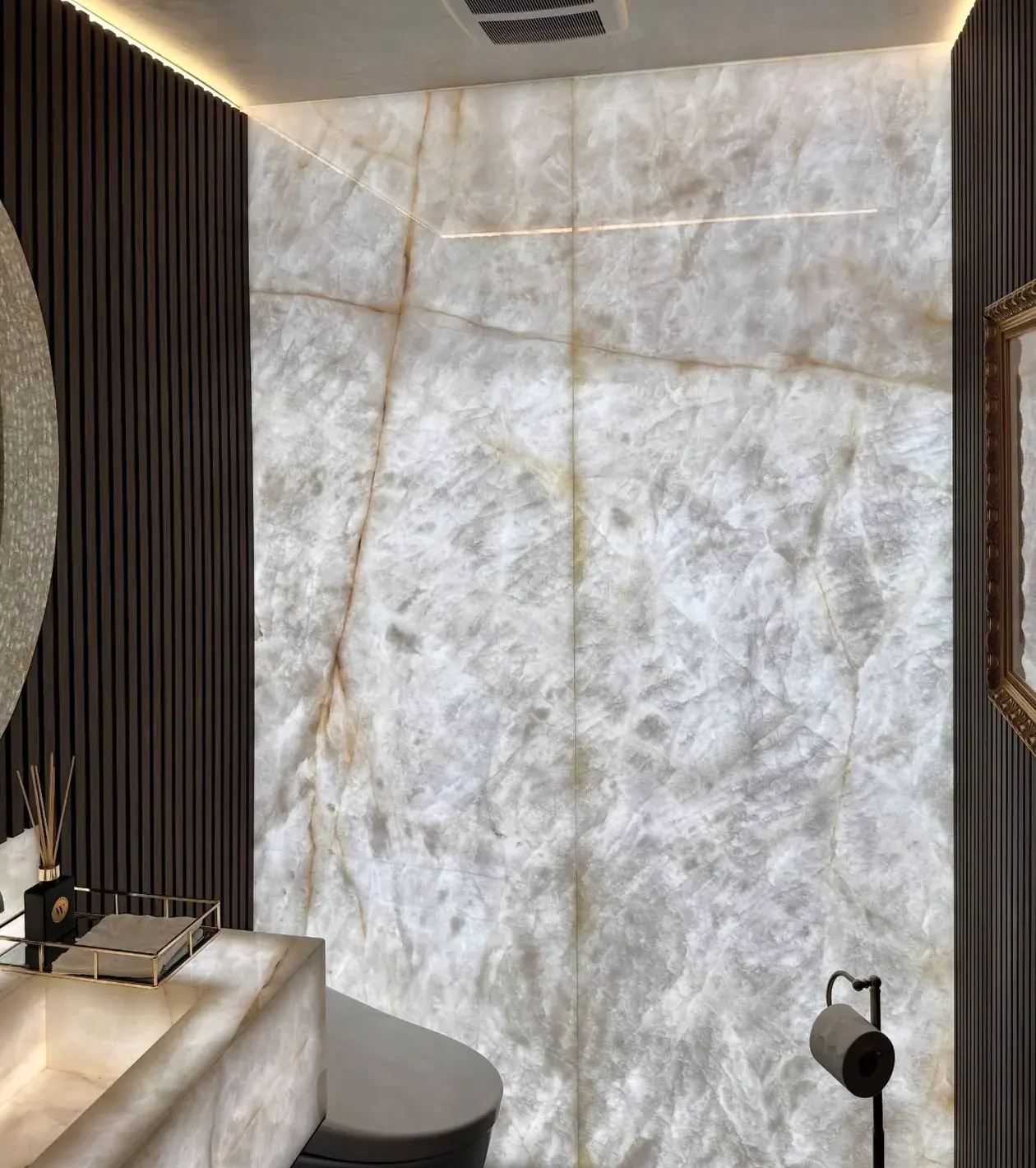 Powder room with backlit Cristallo quartzite slab walls and matching carved stone vanity.